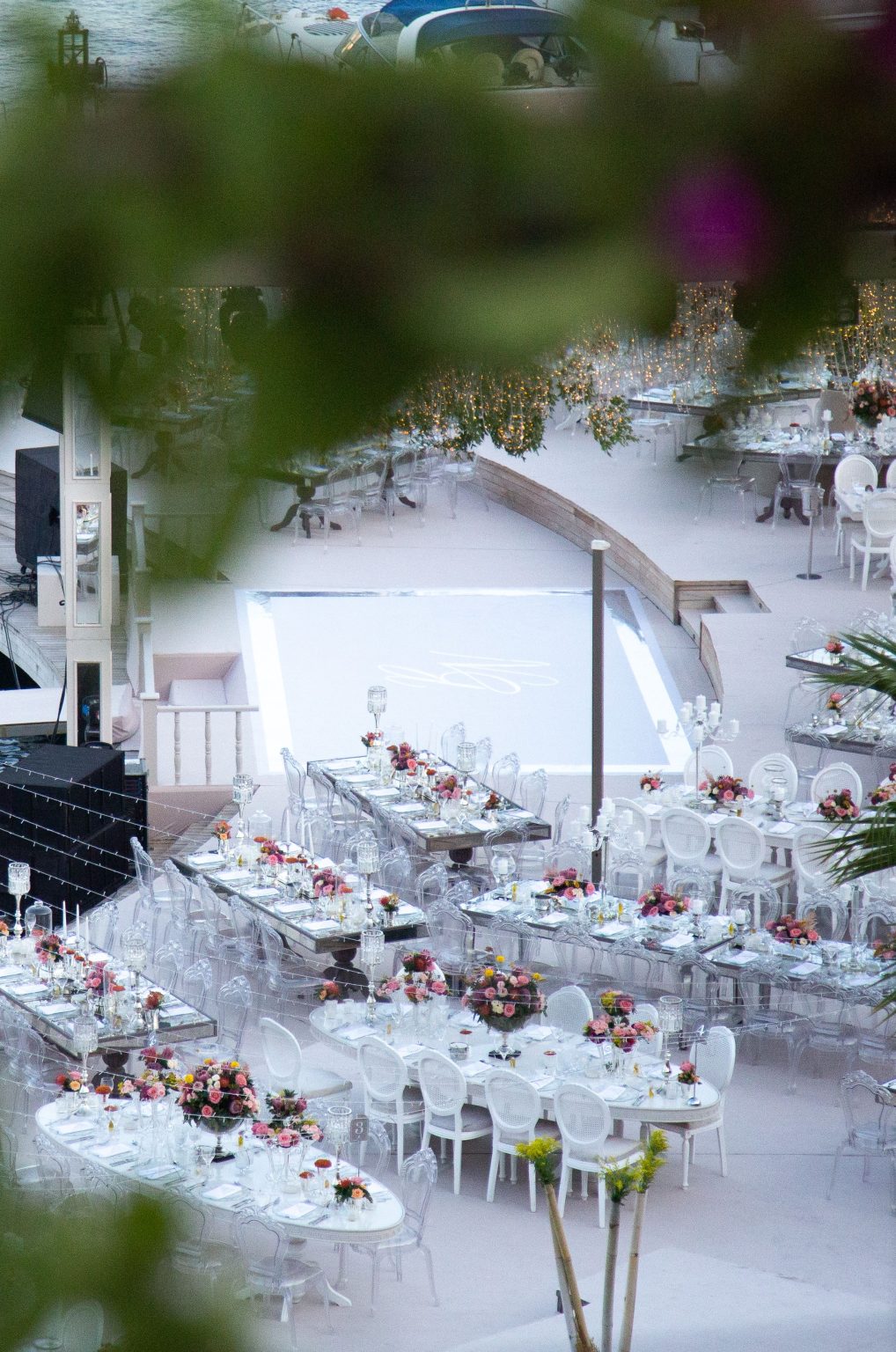 Aerial view of a stylish wedding reception setup outdoors with white tables and floral decor.